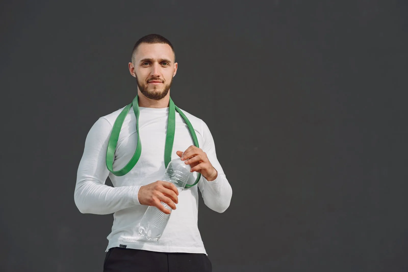 Athletic man with a resistance band and water bottle, ready for workout.